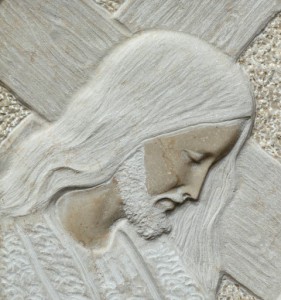 closeup of Jesus holding a cross- detail of relief in stone